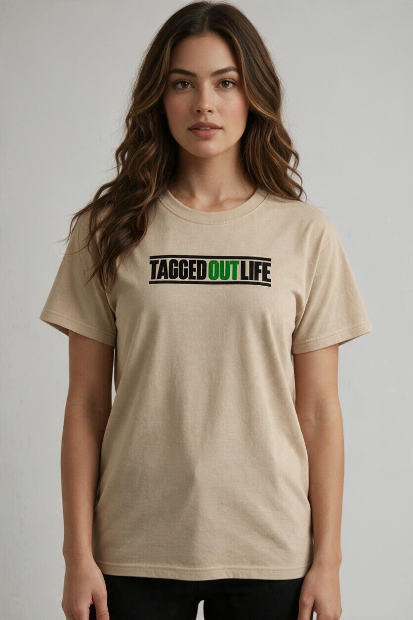 Woman wearing a beige Tagged Out Life short-sleeve unisex hunting t-shirt with a black and green logo graphic.