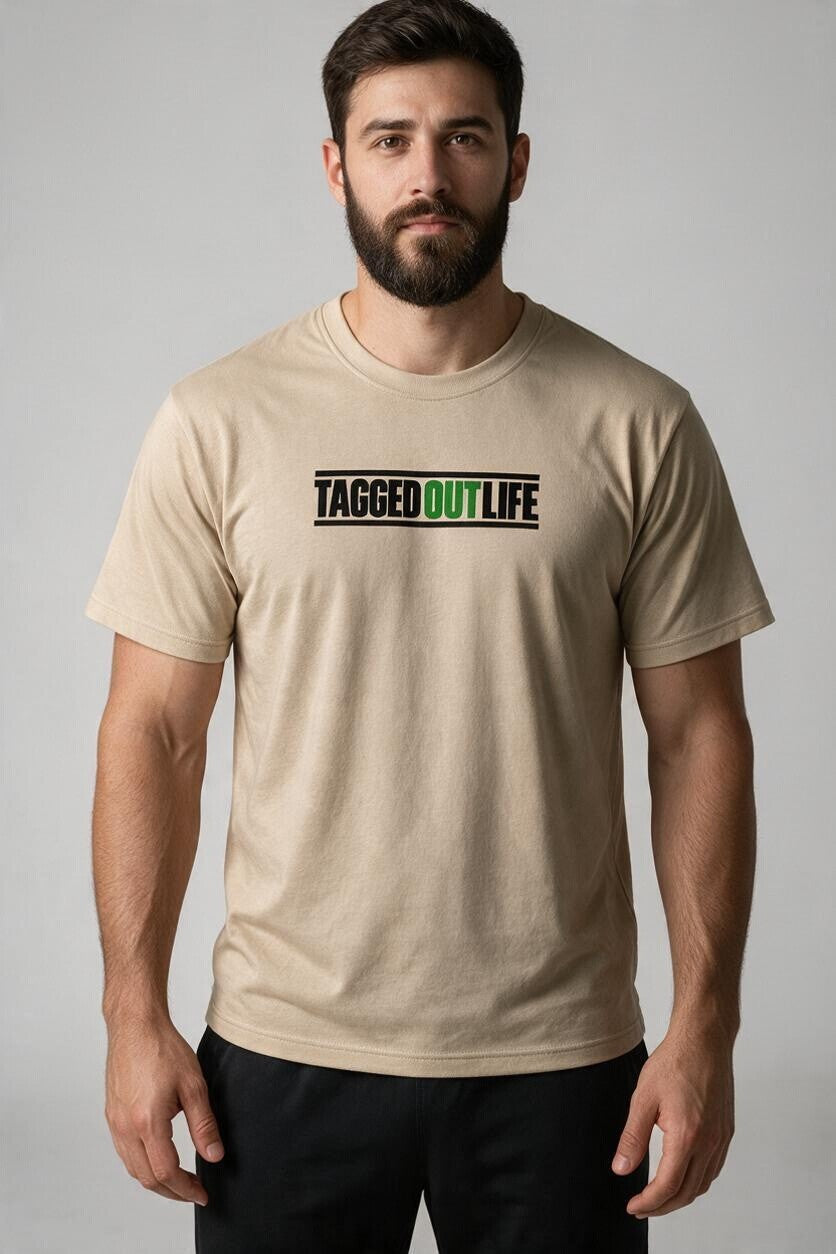 Man wearing a Tagged Out Life beige short-sleeve hunting t-shirt with a black and green logo graphic on the chest